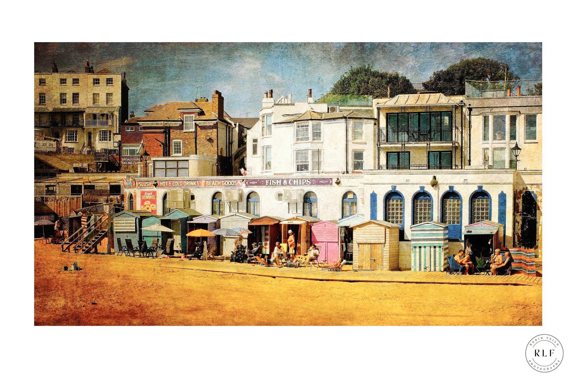 Colourful English seaside scene with pastel beach huts, people relaxing, and period houses in the background. Fine art photography by RLF Photography