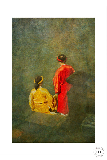 Two women in traditional Vietnamese red and gold robes sitting in contemplation against a textured background