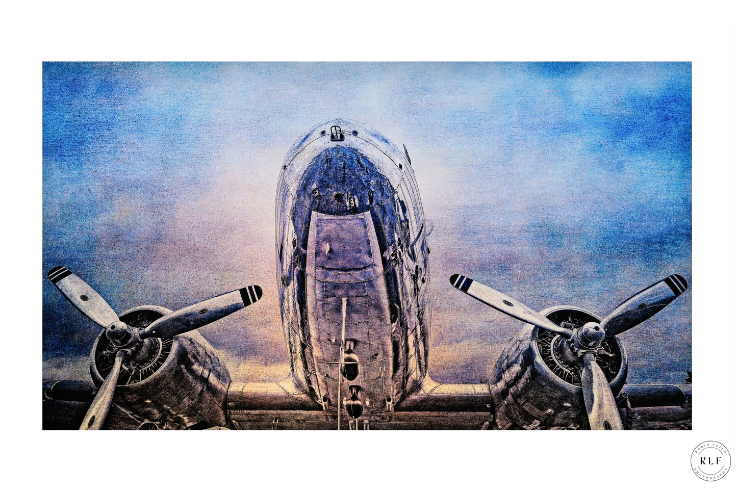 Vintage McDonnell Douglas DC3 vintage aircraft with polished chrome fuselage and propellers, set against a cloudy blue sky. Fine art photography by RLF Photography