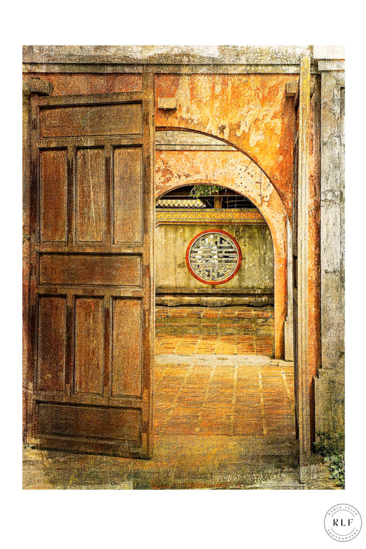 Open doorway in a Vietnamese temple, with ancient symbol set into textured stone wall, soft natural light guiding the viewer’s gaze down a tranquil, timeworn pathway of terracotta flagstones. Fine art photography by RLF Photography